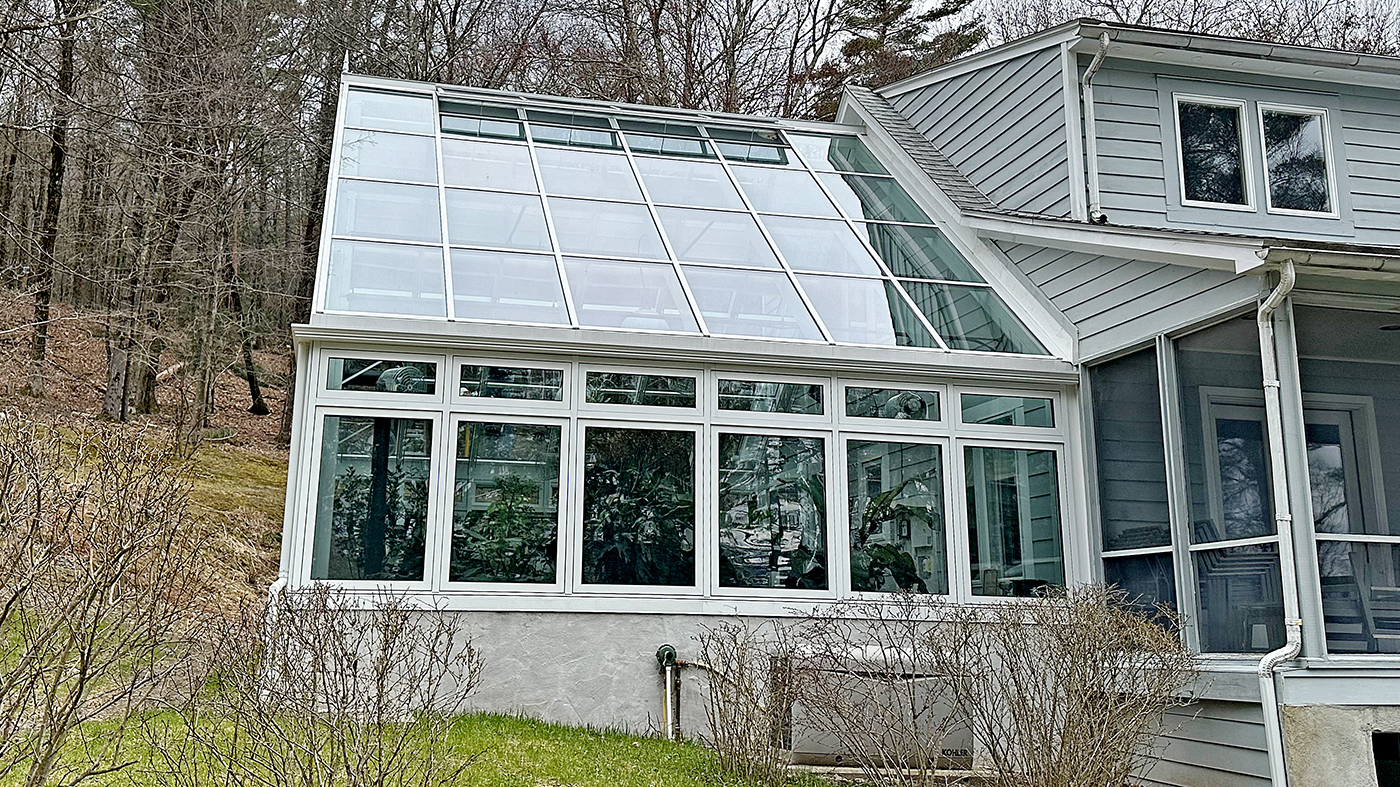 Straight eave double pitch conservatory with 10 motorized and eight manual awning windows, a French door and a solid panel to allow for heater exhaust.
