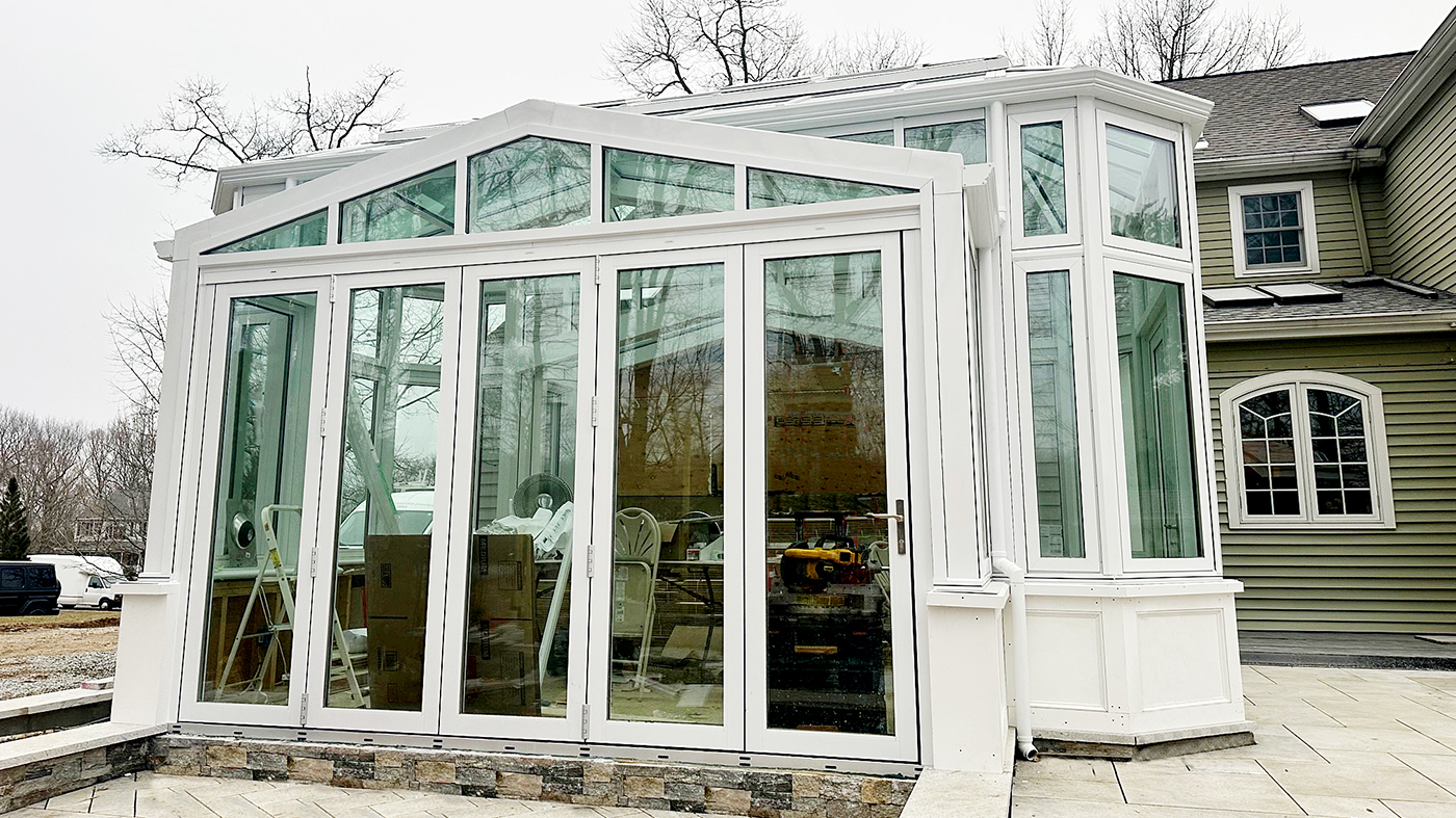 Straight eave double pitch conservatory with a bull nose roof, an integrated five-panel G2 outfold single door last panel (SDLP) bifold door unit and an outswing French door unit.