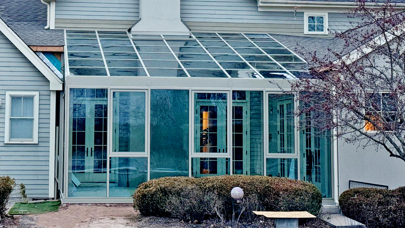Straight eave lean-to sunroom with three awning windows and a sliding glass door unit incorporated into the design.